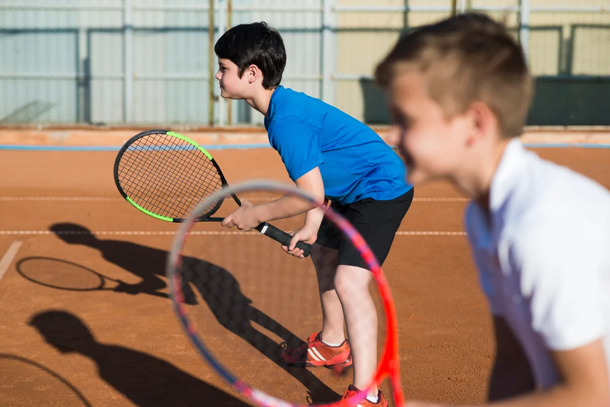 Niños jugando tenis en la cancha